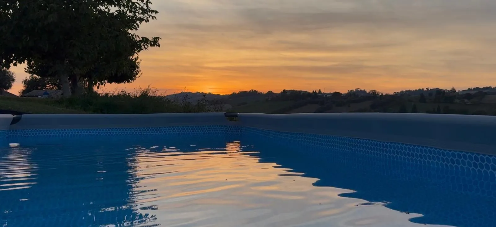 Opzetzwembad bij zonsondergang met uitzicht over de heuvels van Le Marche, Corridonia