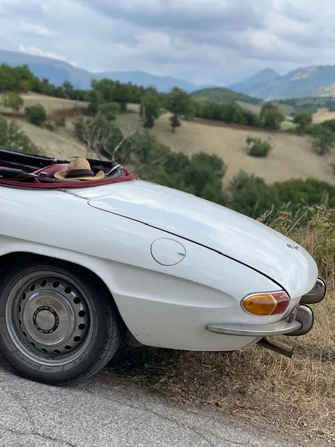 Alfa Romeo Duetto langs de weg met de Monti Sibillini op de achtergrond